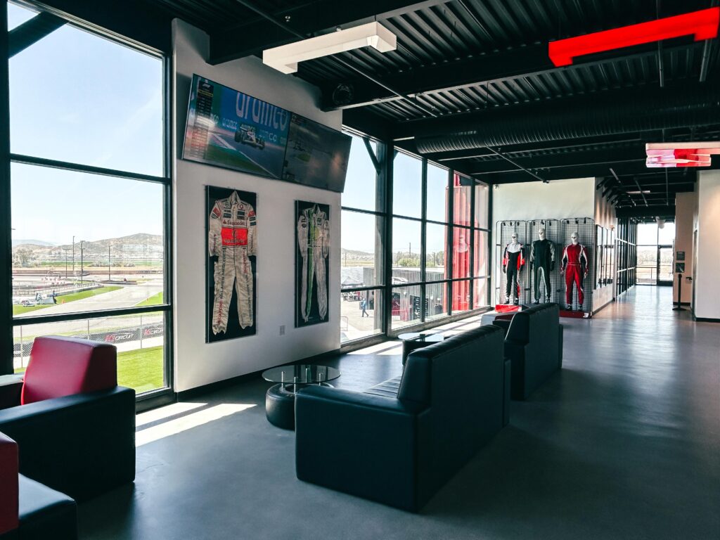 The view from inside the building at K1 Circuit Winchester. Pro Shop suits on the right and used professional racing suits on display with the track visible through the windows