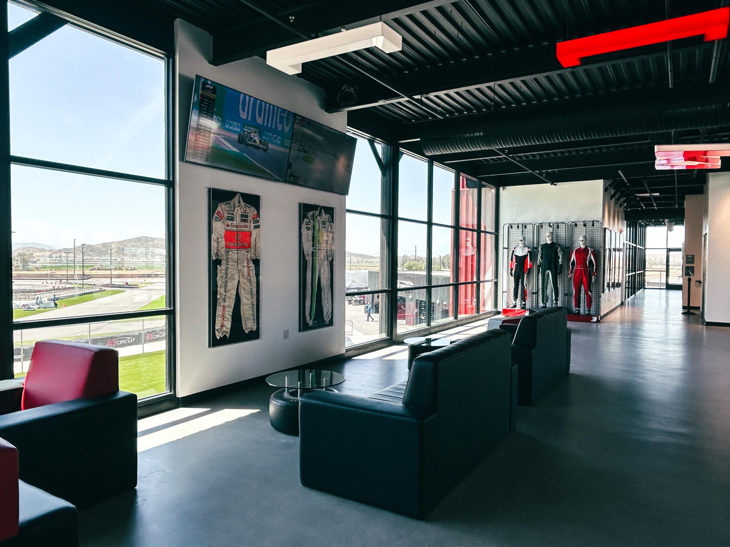 The view from inside the building at K1 Circuit Winchester. Pro Shop suits on the right and used professional racing suits on display with the track visible through the windows