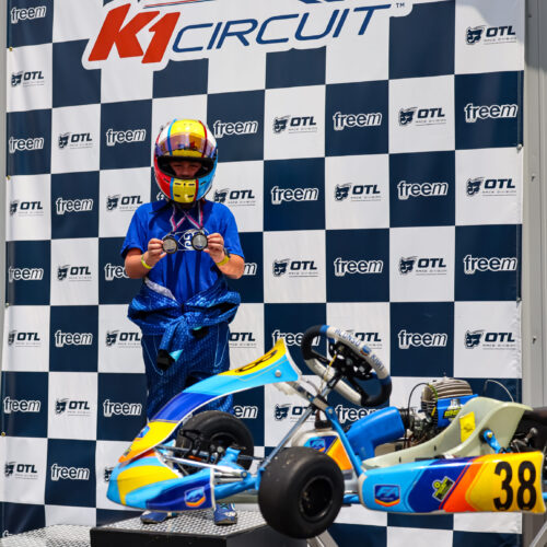 a kart racer stands on the podium at k1 circuit whiteland with his kart and two medals